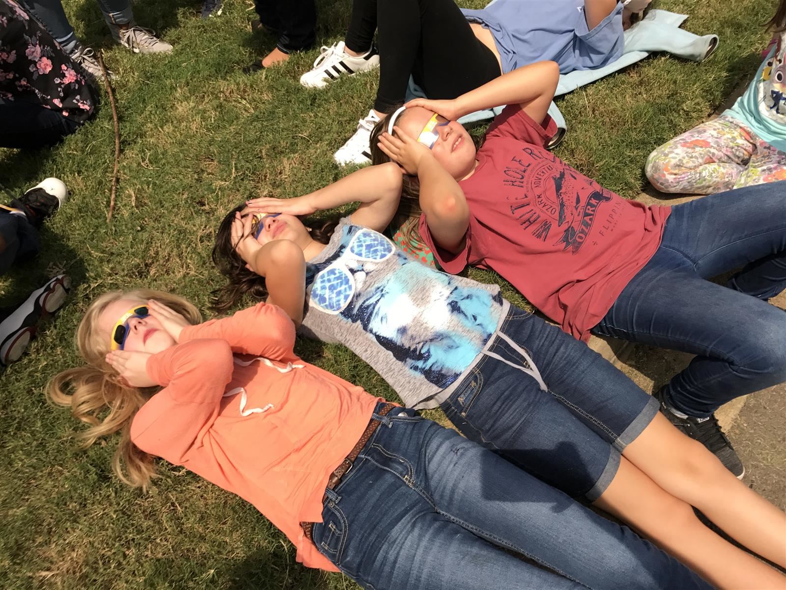 students laying down watching the eclipse